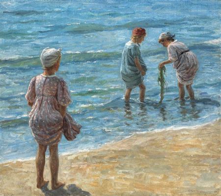 Children playing with seaweed at the water's edge on Skagen beach