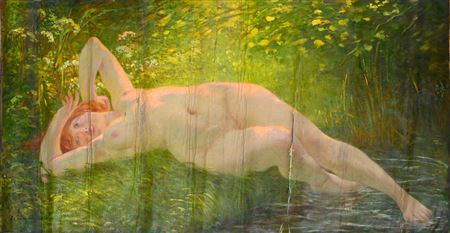 Young red-haired woman lying on the grass with one foot in the water