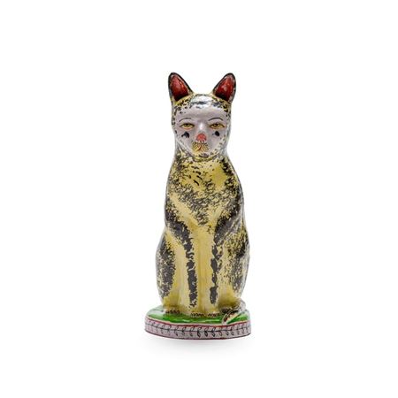 A yellow and black cat perched on a round base