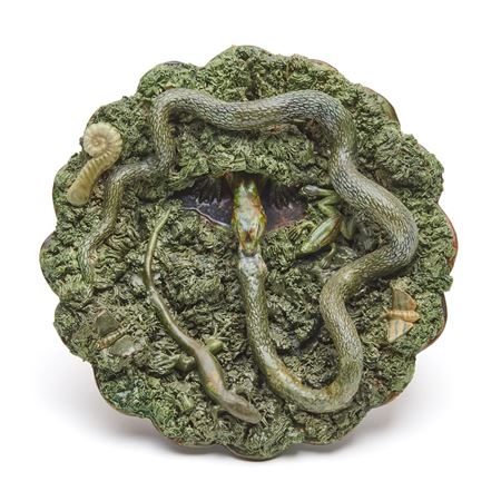 Plate with lizard in den eating a snake