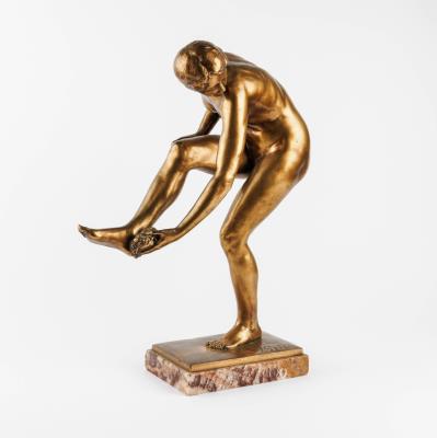 A bronze figure of a woman bathing