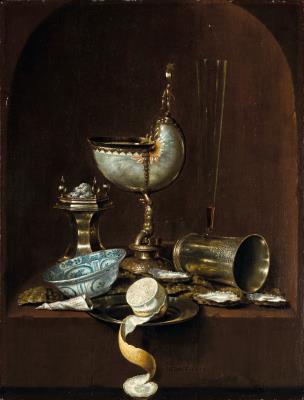 Still life with a silver-gilt-mounted nautilus cup, a beaker on its side, a peeled lemon on a plate, oyster shells, a blue and white porcelain bowl, a silver salt cellar and other objects on a stone ledge, in an arched niche