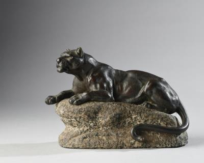 Bronze figure of a lioness, recumbent but alert on a granite rock