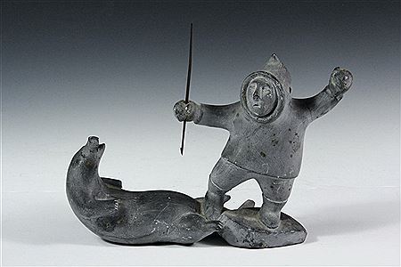 Gray Stone Inuit Carving of Hunter Standing Over Seal, both arms raised