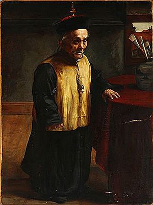An elderly Chinese dwarf in traditional dress standing by a table
