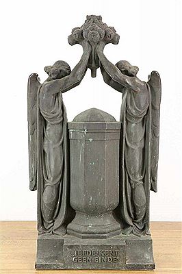 Two women flank an urn, together beaten hands