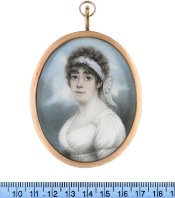 A Lady, wearing white dress, a white bandeau tied at the back of her dark curled hair.