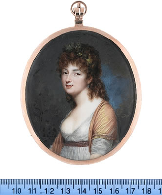 A Lady, wearing white dress, brown belt, gold stole with brown borders, pearl pendent earring, a wreath of leaves in her loose curled hair.