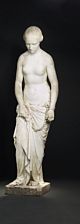 Female slave. Standing, half naked, her hands in chains