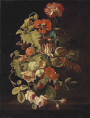 A carnation, iris, roses, tulips and other flowers in a glass vase on a stone ledge
