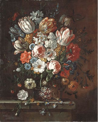 Roses, parrot tulips, an iris, narcissi and other flowers in a glass vase on a stone ledge