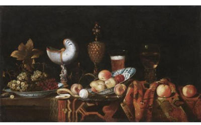 Still life with pears, apples, grapes in a ceramic bowl, a partly peeled lemon, a nautilus cup, a roemer and a beer glass, all arranged on a table partly draped with a carpet