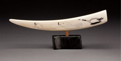 Engraved tusk depicting animals, and a hunter and dog chasing a polar bear