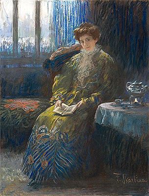 L’heure bleue. Junge Dame in grünlichem, mit Pfauenmotiven gemustertem Kleid am Teetisch, im Schoß Almanach
