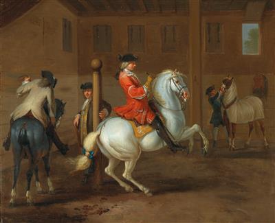 A cavalier on a gray horse in a riding school